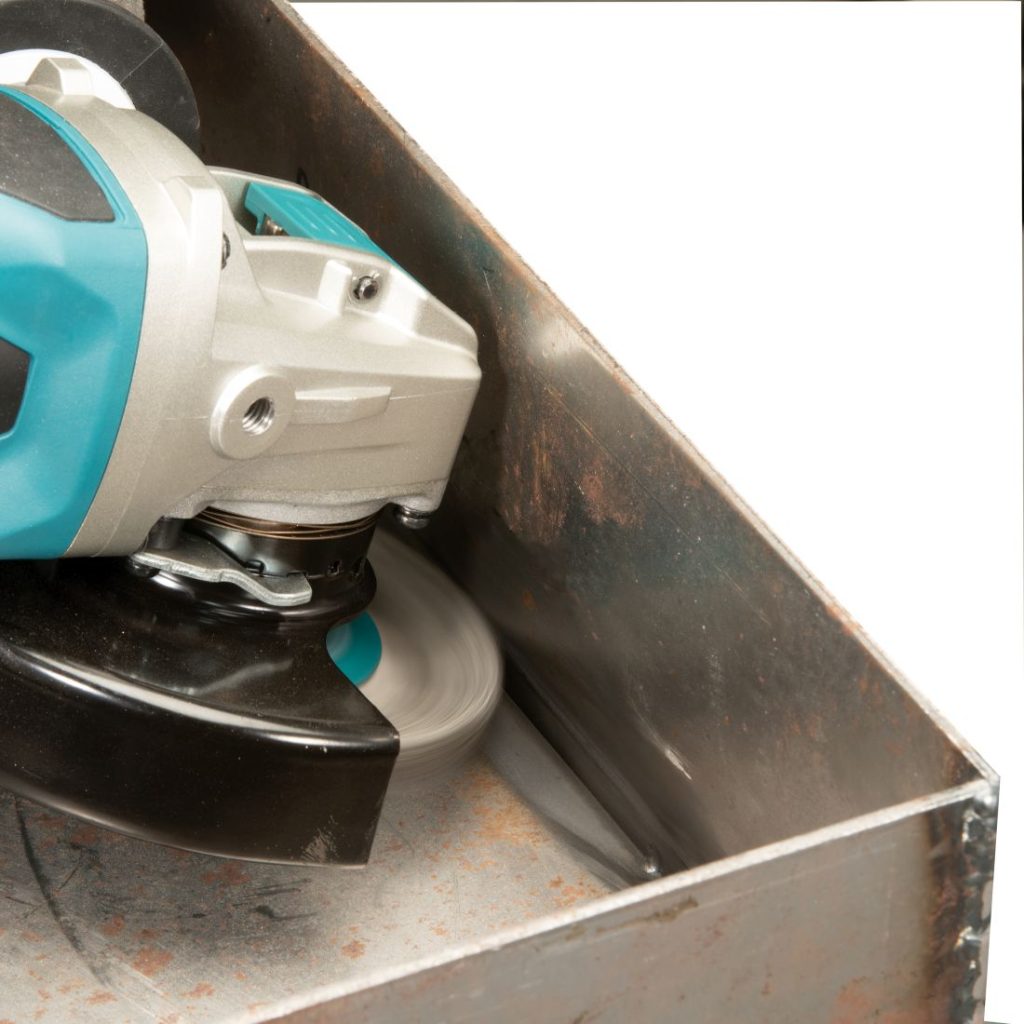 MAKITA Teräsharja 115 mm X-Lock. Kuvassa hiotaan laikkaharjalla hitsatun teräslaatikon sisäkulmia.