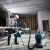 MAKITA Jiirisahajalusta WST07. Kuvassa henkilö sahaamassa lautaa jiirisahajalustan päällä olevalla jiirisahalla. Etualalla jiirisahaan liittetty imuri.