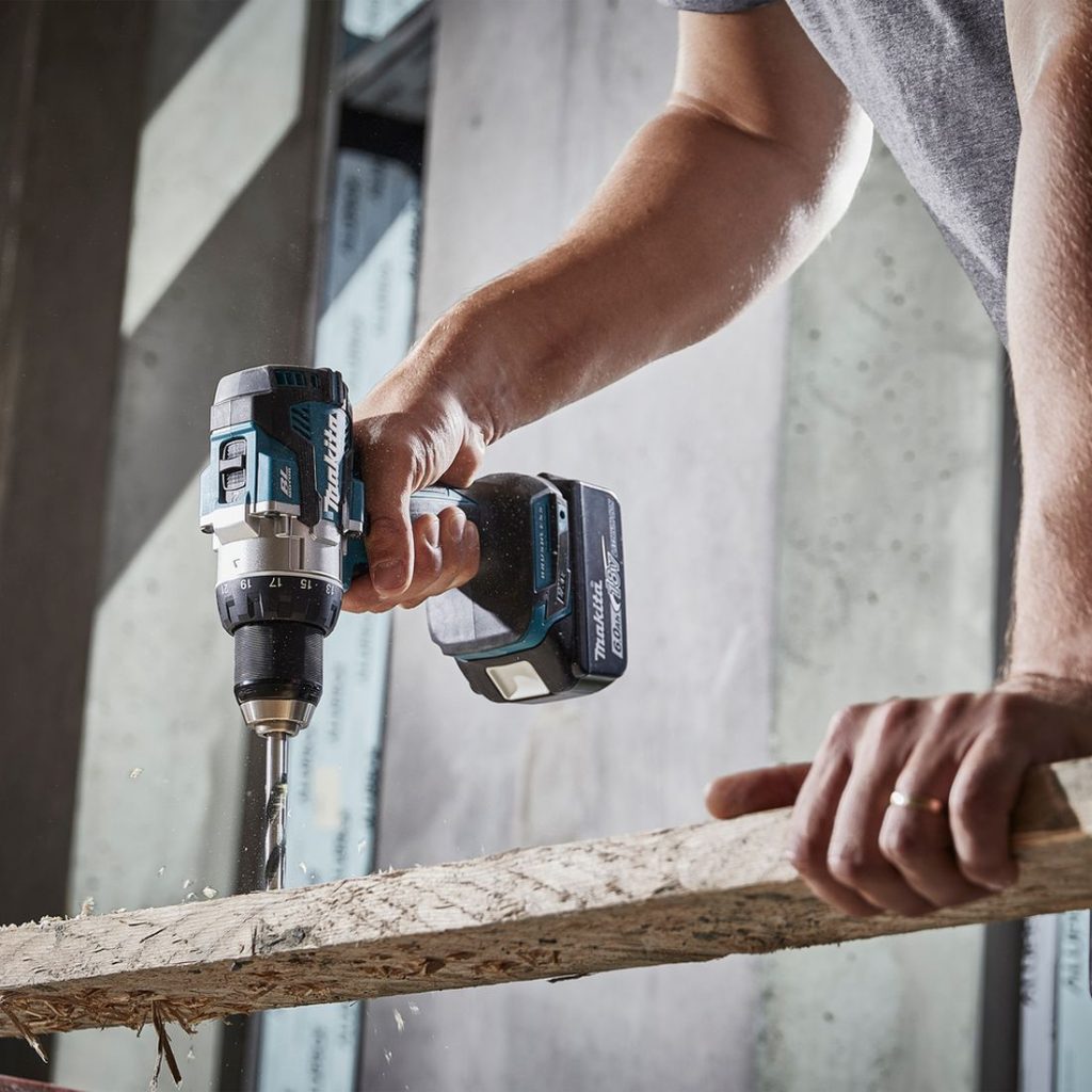 MAKITA Porakone LXT. Kuvassa henkilö poraamassa reikää lautaan.