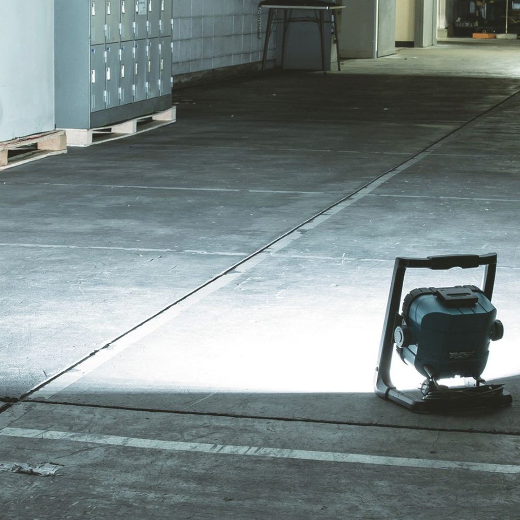 MAKITA LED-valaisin LXT. Kuvassa LED-valaisin LXT työmaakäytössä vasemmalta takayläviistosta valaisimen valaistessa holvin lattiaa.
