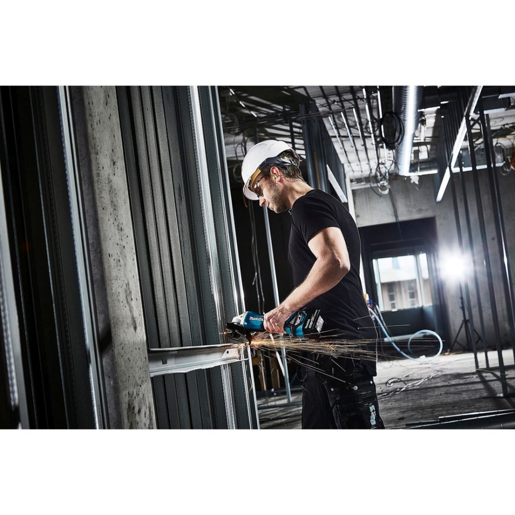 MAKITA Kulmahiomakone LXT. Kuvassa henkilö katkaisemassa alumiiniprofiilia kulmahiomakone LXT:n avulla.
