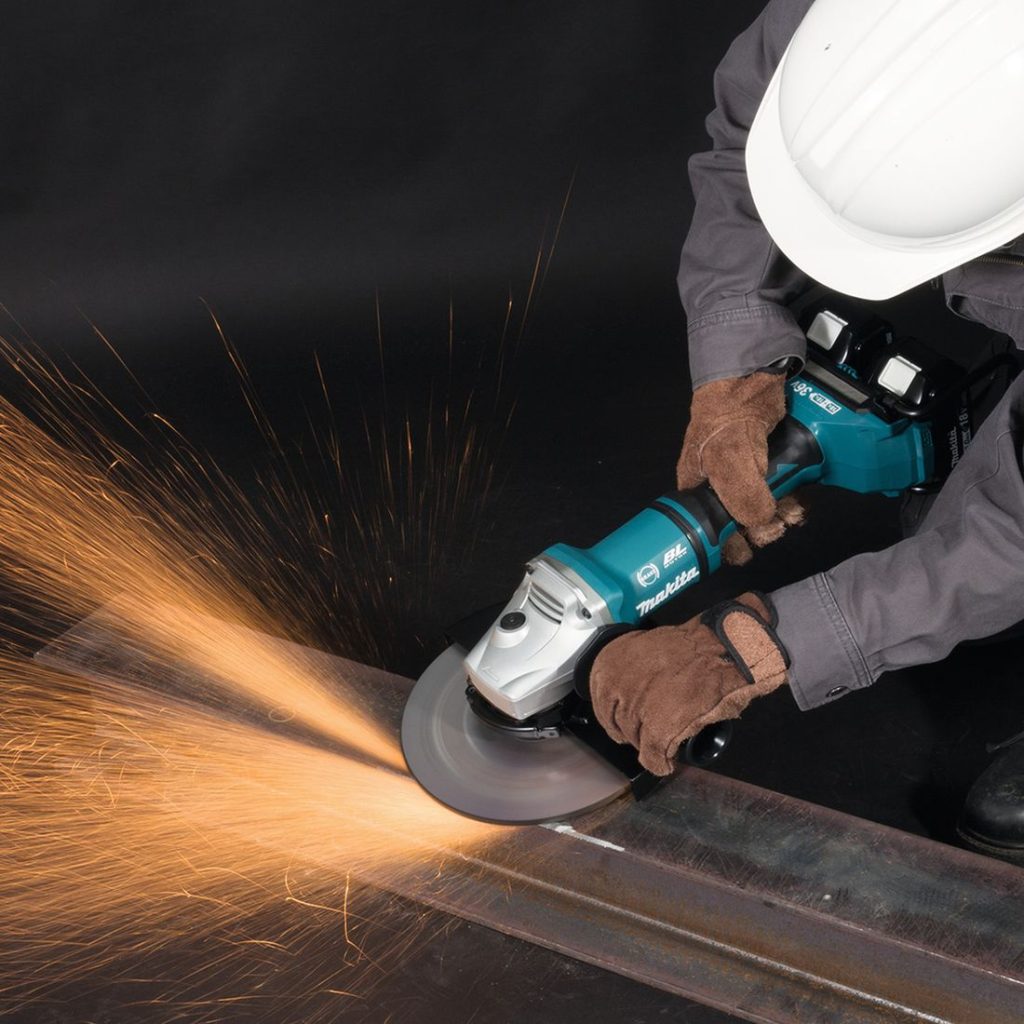 MAKITA Kulmahiomakone LXT. Kuvassa henkilö hiomassa teräs I-palkkia kulmahiomakone LXT:n avulla.