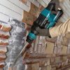 MAKITA Piikkausvasara LXT. Kuvassa henkilö piikkaamassa koristelaatoitusta seinästä Piikkausvasara LXT:n avulla.