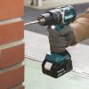 MAKITA Iskuporakone LXT. Kuvassa henkilö poraamassa reikää tiiliseinään iskuporakoneen avulla.