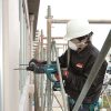 MAKITA Poravasara LXT. Kuvassa henkilö rakennustelineellä poraamassa reikää betoniseinään Poravasara LXT:n avulla.