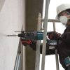 MAKITA Poravasara LXT. Kuvassa henkilö rakennustelineellä poraamassa reikää betoniseinään Poravasara LXT:n avulla.