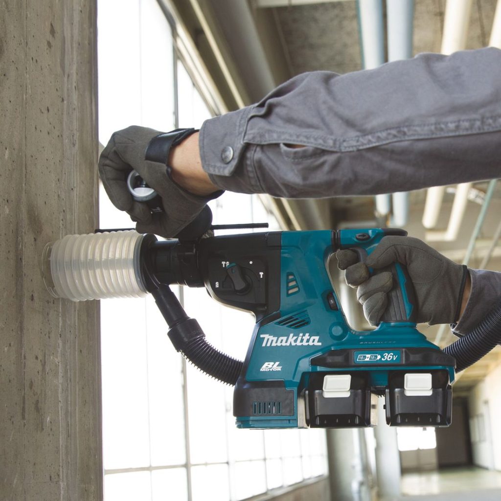 MAKITA Poravasara LXT. Kuvassa henkilö poraamassa betoniseinään reikää Poravasara LXT:n avulla pölykuppia käyttäen.