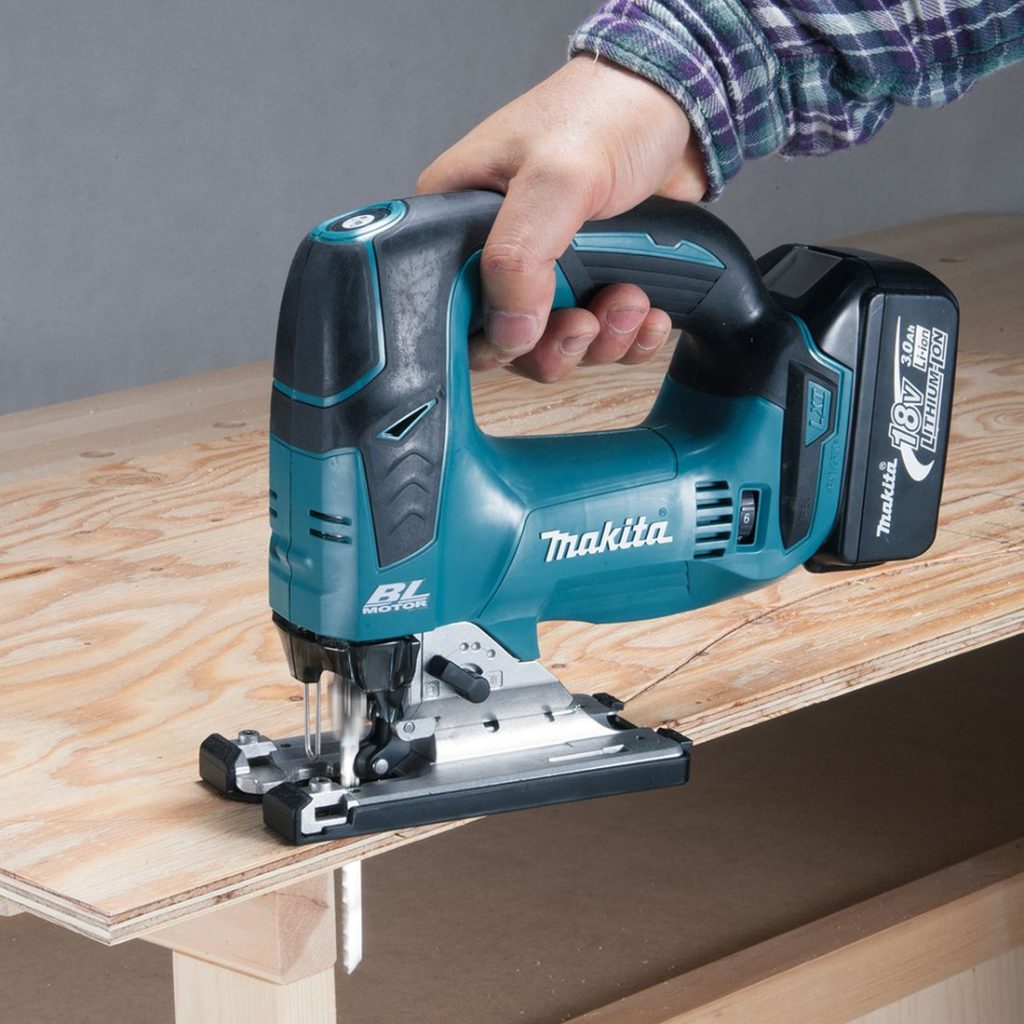 MAKITA Pistosaha LXT. Kuvassa henkilö sahaamassa kaarevaa kuviota vanerilevyyn Pistosaha LXT:n avulla.