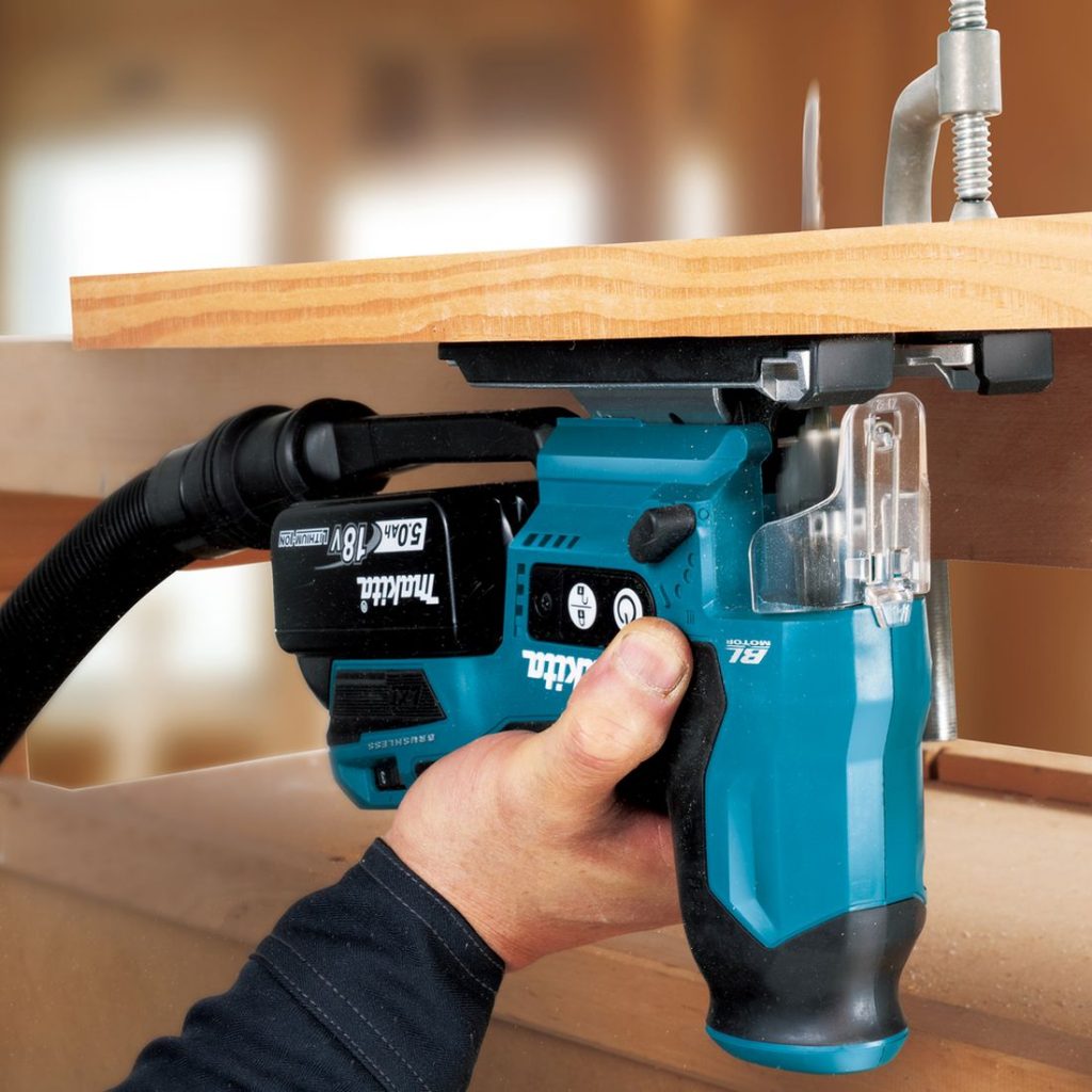 MAKITA Pistosaha LXT. Kuvassa henkilö sahaamassa puulevyä levyn alapuolelta Pistosaha LXT:n avulla.