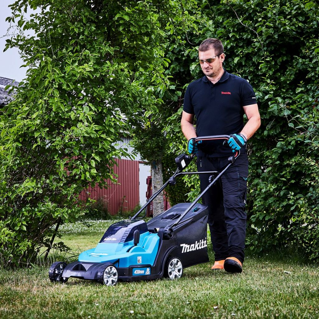 MAKITA Ruohonleikkuri LXT. Kuvassa henkilö leikkaamassa ruohoa ruohonleikkuri LXT:n avulla.