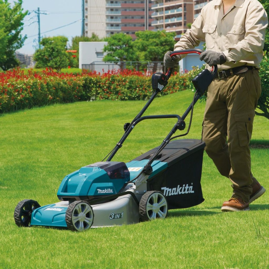 MAKITA Ruohonleikkuri LXT. Kuvassa henkilö leikkaamassa ruohoa ruohonleikkuri LXT:n avulla.
