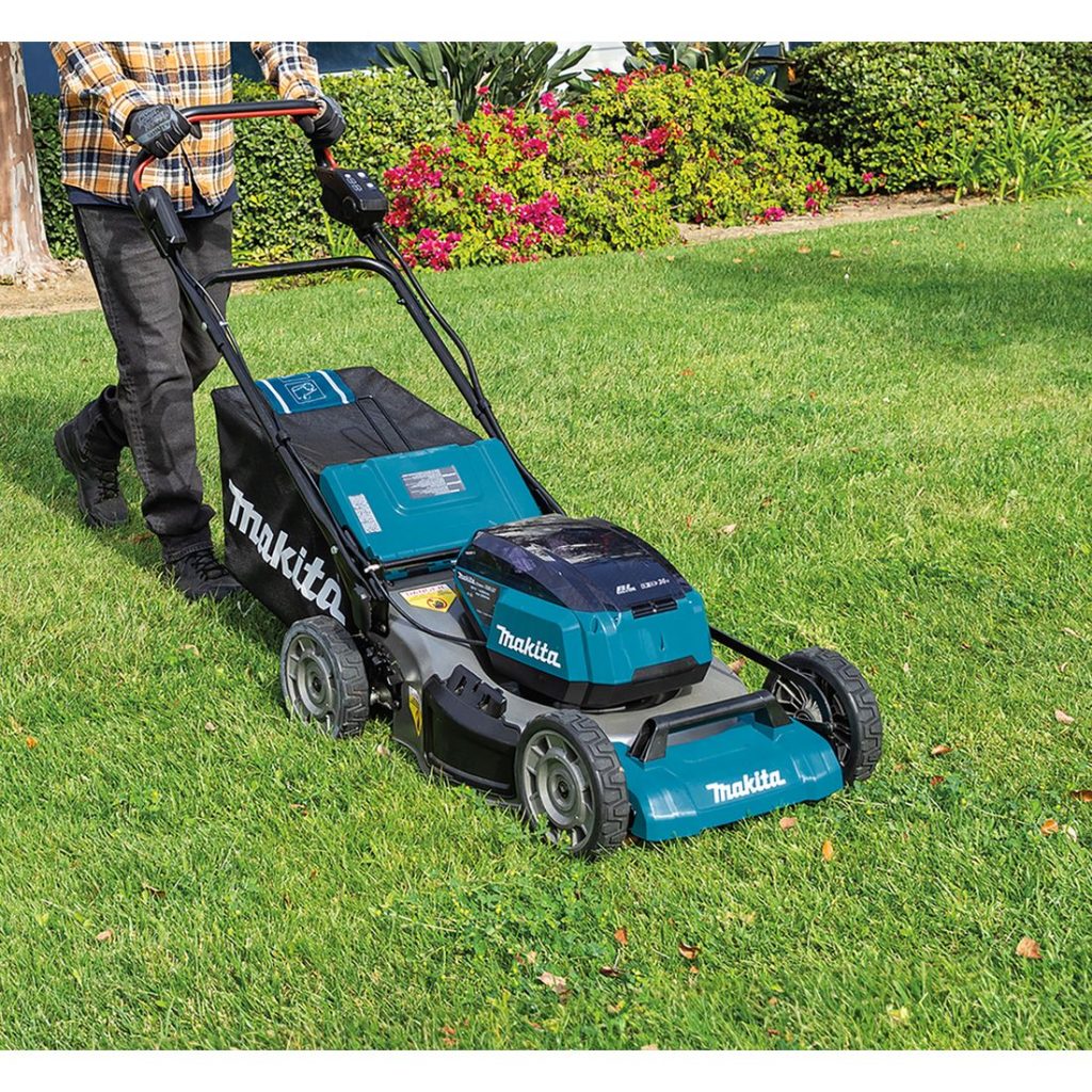 MAKITA Ruohonleikkuri LXT. Kuvassa henkilö leikkaamassa ruohoa ruohonleikkuri LXT:n avulla.