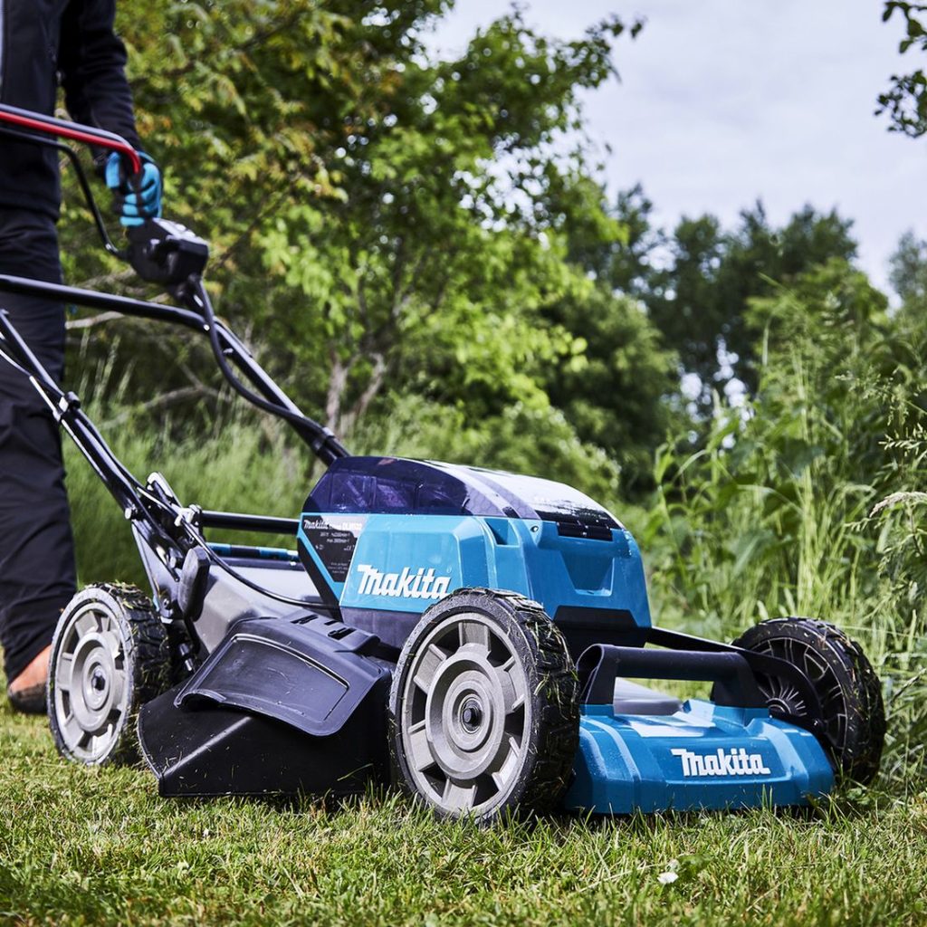 MAKITA Ruohonleikkuri LXT. Kuvassa henkilö leikkaamassa ruohoa ruohonleikkuri LXT:n avulla.