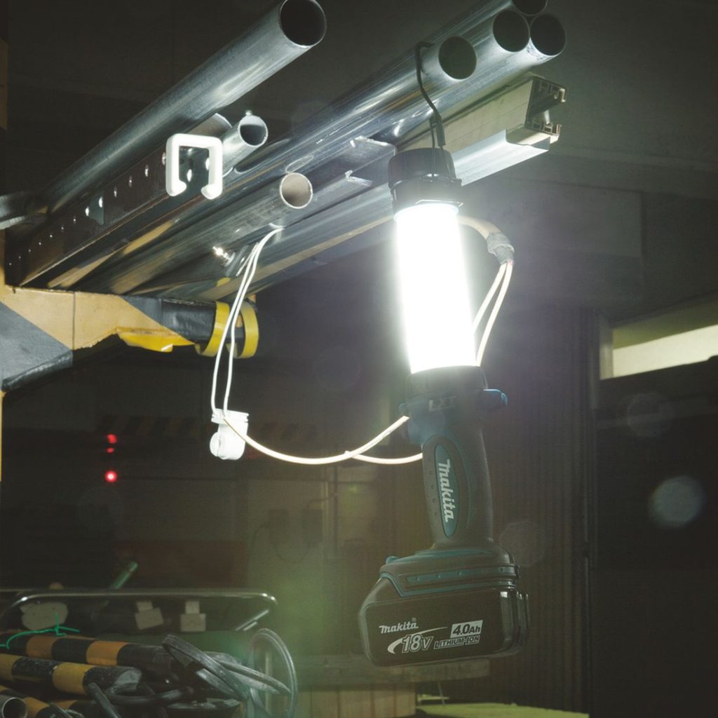 MAKITA LED-valaisin LXT. Kuvassa LED-valaisin LXT ripustettuna putkeen varastossa.