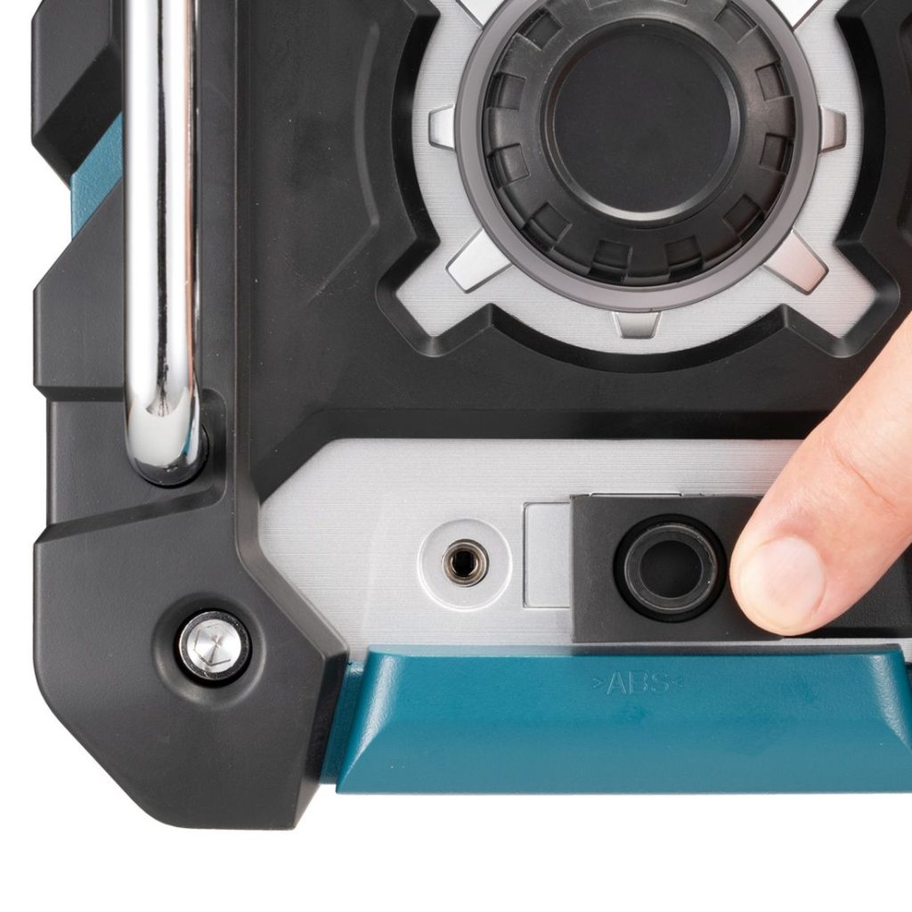 MAKITA Radio CXT / LXT. Lähikuvassa henkilö osoittamassa sormellaan Radio CXT / LXT:n AUX-liitäntää.