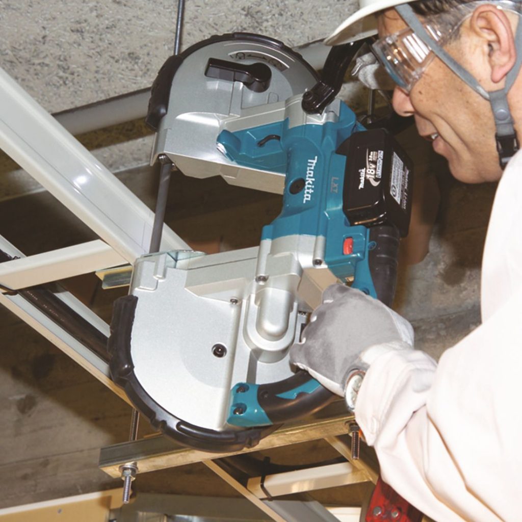 MAKITA Vannesaha LXT. Kuvassa henkilö sahaamassa katosta roikkuvaa metallista kaapelin kannatinta Vannesaha LXT:n avulla.