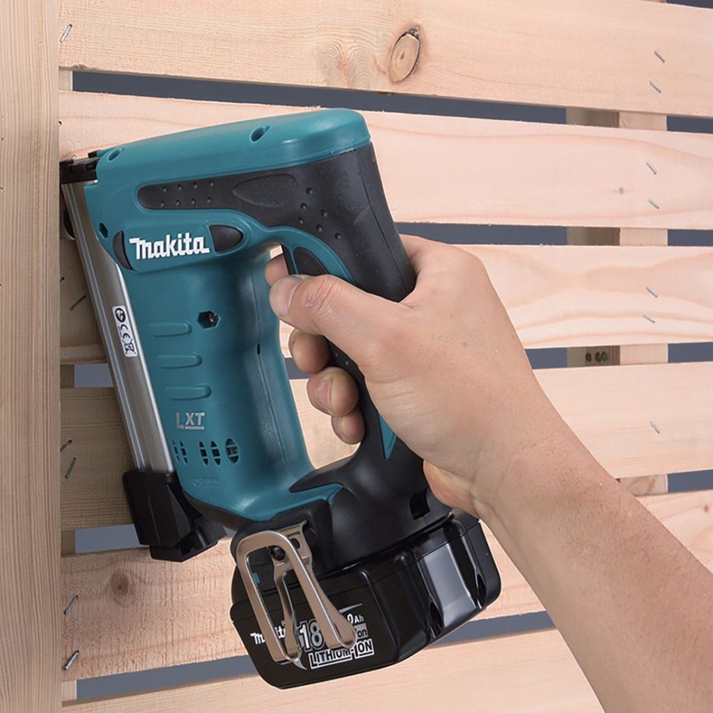 MAKITA Hakasnaulain LXT. Kuvassa henkilö naulaamassa rimaa puuaitaan Hakasnaulain LXT:n avulla.
