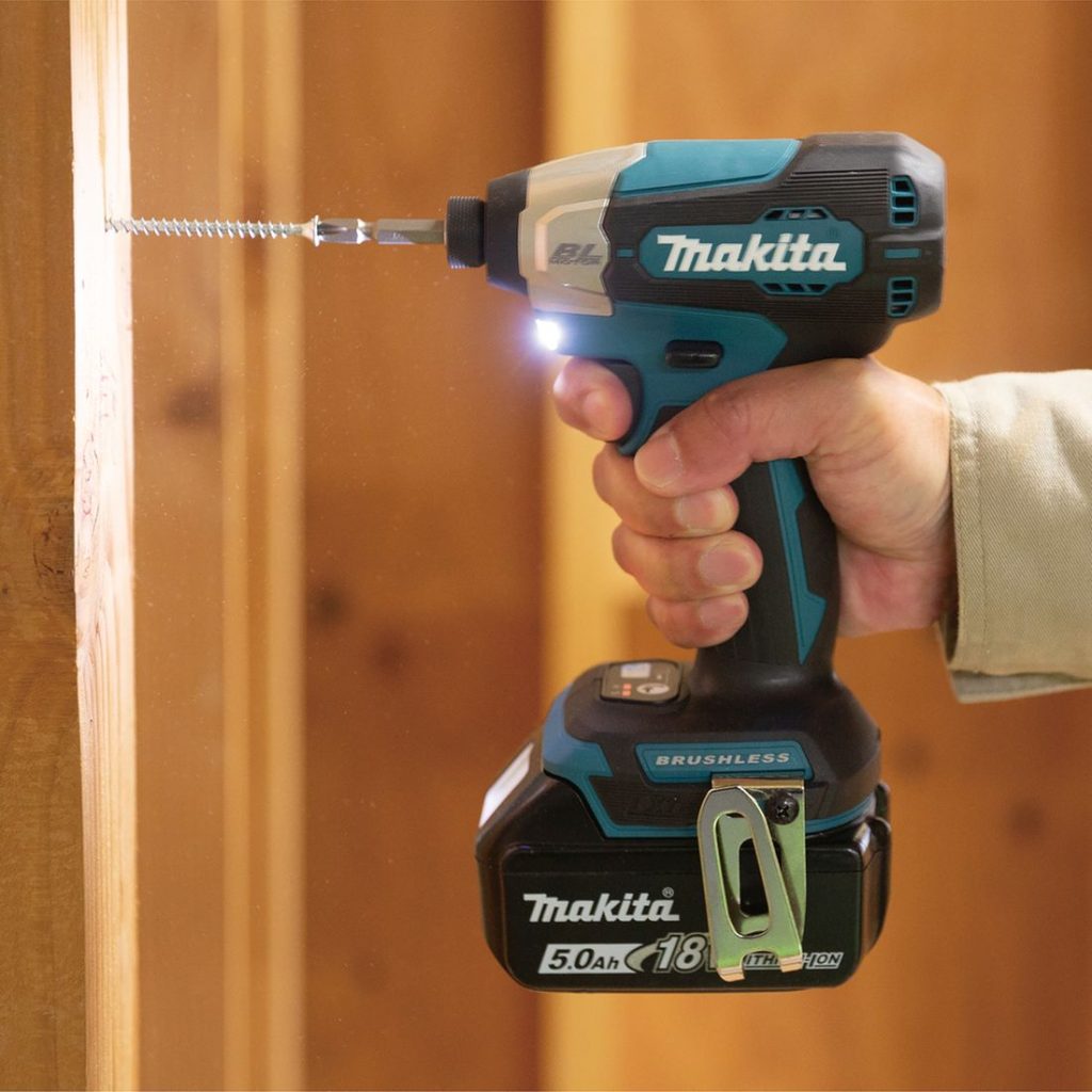 MAKITA Iskevä ruuvinväännin LXT. Kuvassa henkilö ruuvamassa ruuvia puurunkoon Iskevä ruuvinväännin LXT:n avulla.