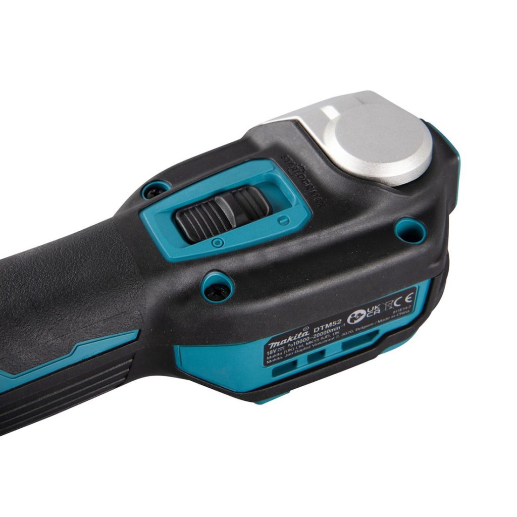 MAKITA Monitoimikone LXT. Lähikuvassa Monitoimikone LXT:n käynnistyskytkin oikealta takayläviistosta.