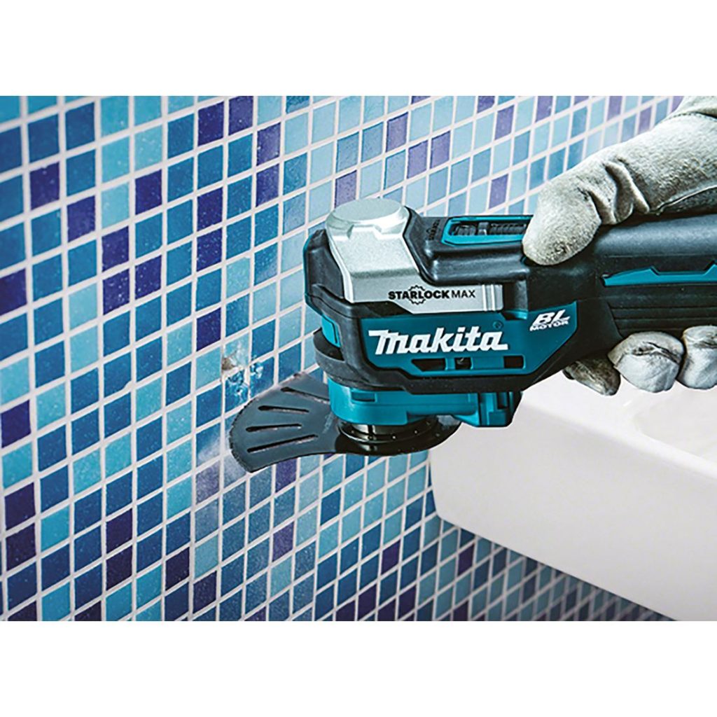 MAKITA Monitoimikone LXT. Kuvassa henkilö irrottamassa kaakelisaumoja kylpyhuoneen kaakeliseinästä Monitoimikone LXT:n avulla.
