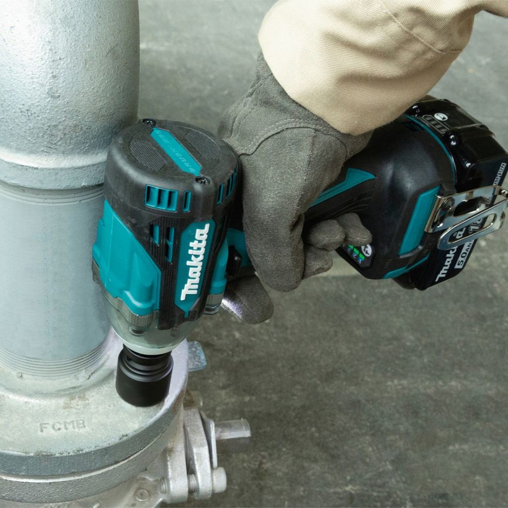 MAKITA Iskevä mutterinväännin LXT. Kuvassa henkilö kiristämässä pulttia putken laippaan Iskevä mutterinväännin LXT: avulla.