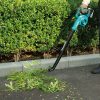MAKITA Puhallin LXT. Kuvassa henkilö puhaltamassa pensaan lehtiä Puhallin LXT:n avulla.