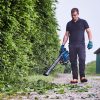 MAKITA Puhallin LXT. Kuvassa henkilö puhaltamassa puun lehtiä kadulla Puhallin LXT:n avulla.