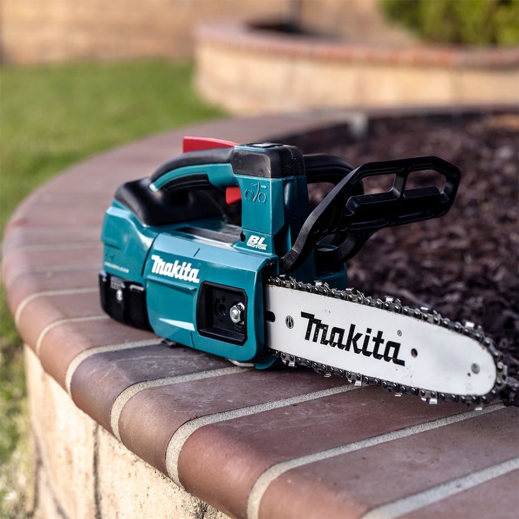 MAKITA Ketjusaha LXT. Kuvassa Ketjusaha LXT istutuksen juurisuojan reunan päällä.