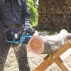 MAKITA Ketjusaha LXT. Kuvassa henkilö sahaamassa kaatunutta puuta pukkien päällä Ketjusaha LXT: avulla.