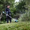 MAKITA Ruohotrimmeri LXT. Kuvassa henkilö trimmaamasssa nurmikkoa pensaan vierestä Ruohotrimmeri LXT:n avulla.