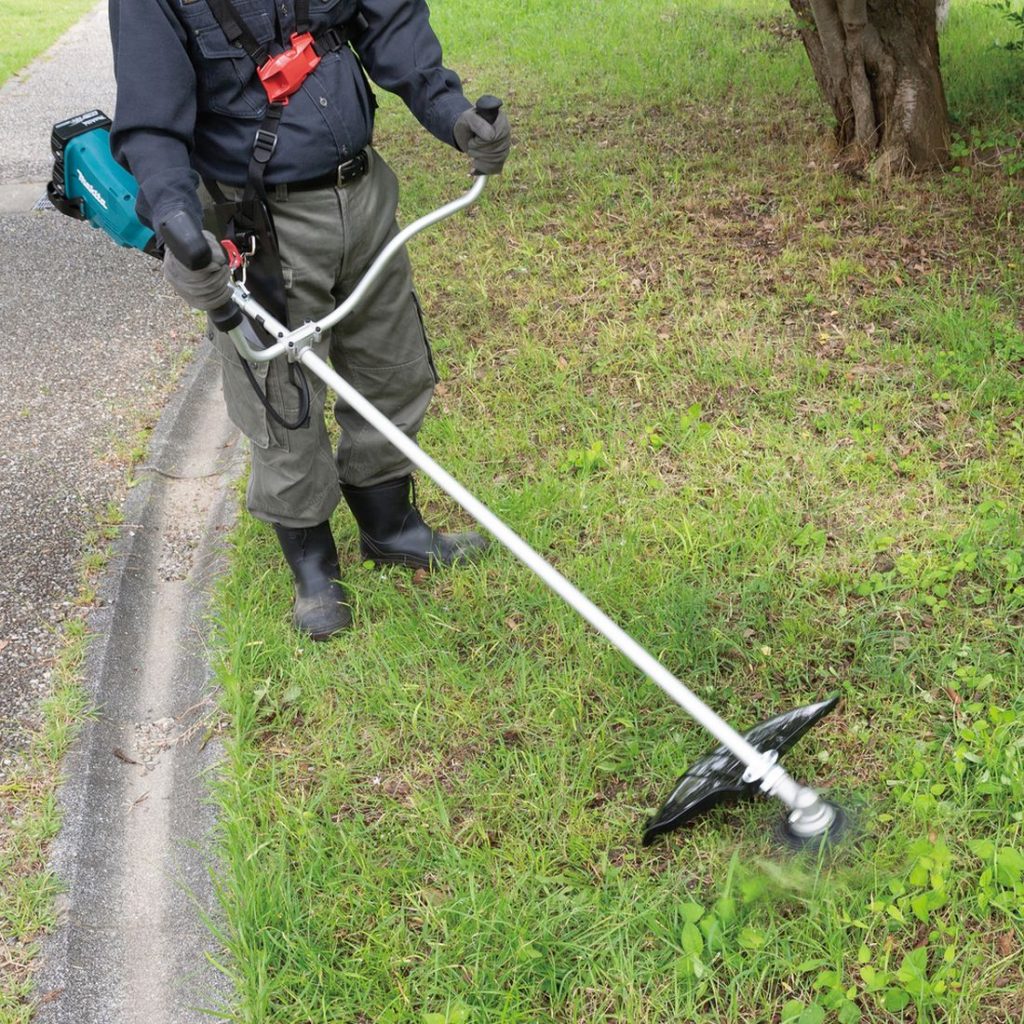 MAKITA Ruohoraivuri LXT. Kuvassa henkilö trimmaamassa nurmikkoa Ruohoraivuri LXT:n avulla.