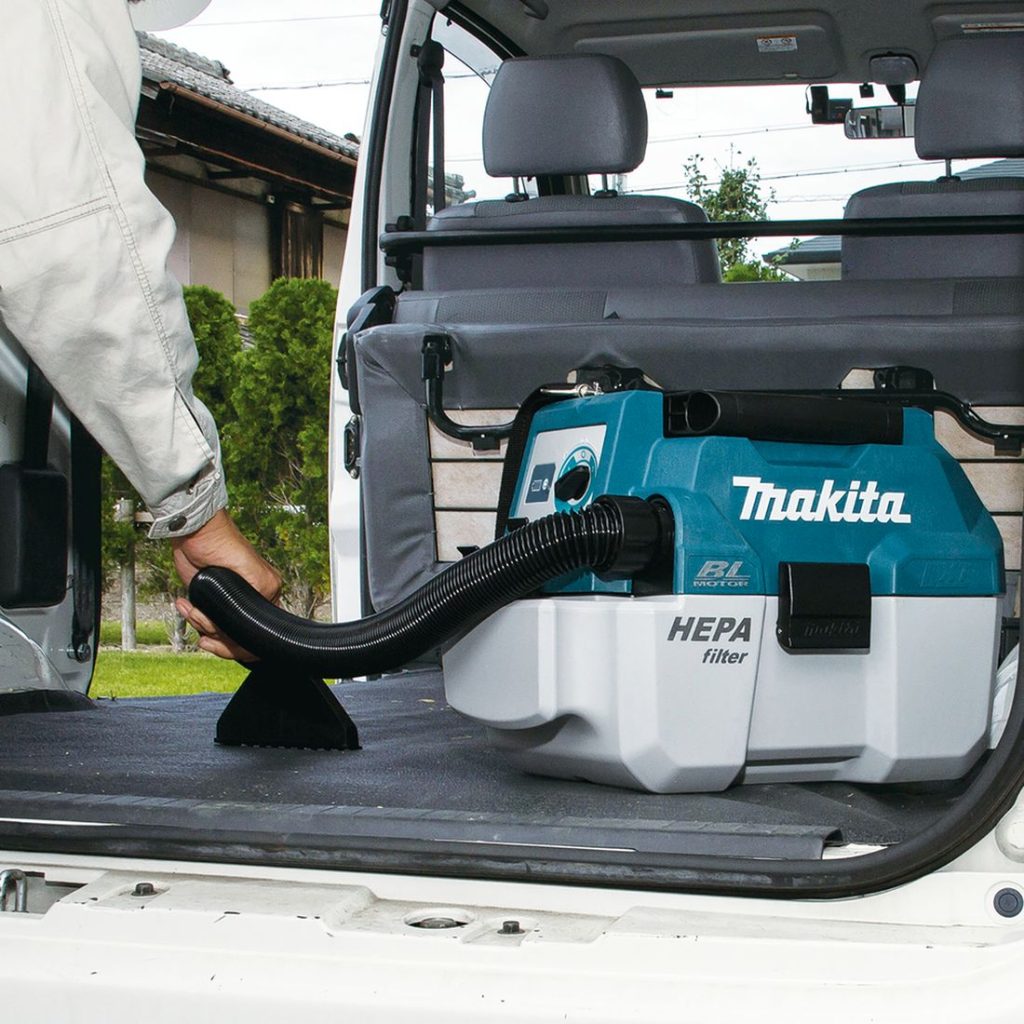 MAKITA Kuivaimuri LXT. Kuvassa henkilö imuroimassa pakettiauton tavaratilan lattiaa Kuivaimuri LXT:n avulla.