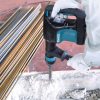 MAKITA Piikkausvasara. Kuvassa henkilö piikkaamassa betonilattiaa piikkausvasaran avulla.