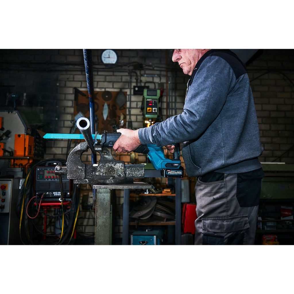 MAKITA Puukkosaha XGT. Kuvassa henkilö katkaisemassa teräsputkea Puukkosaha XGT:n avulla.