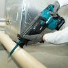 MAKITA Puukkosaha XGT. Kuvassa henkilö katkaisemassa PVC-putkea Puukkosaha XGT:n avulla.