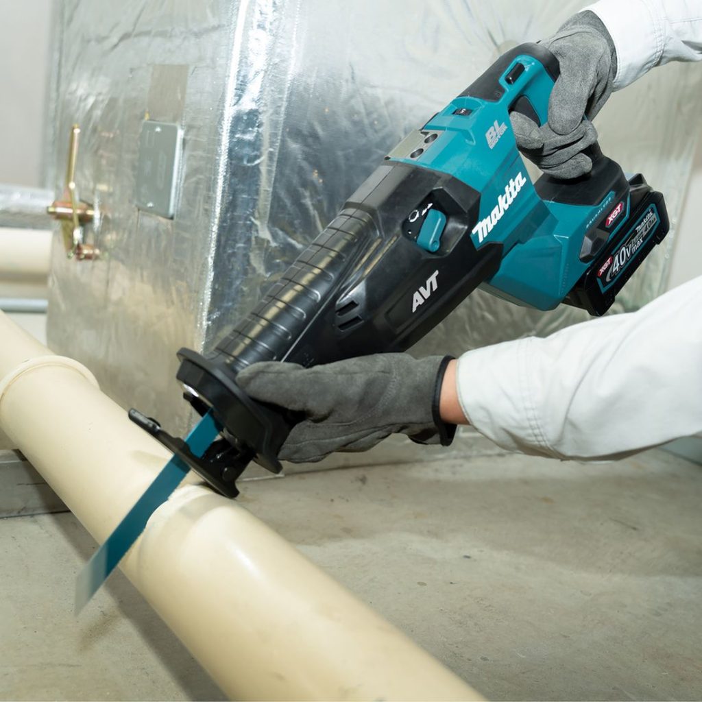 MAKITA Puukkosaha XGT. Kuvassa henkilö katkaisemassa PVC-putkea Puukkosaha XGT:n avulla.