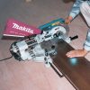 MAKITA Katkaisu- ja jiirisaha. Kuvassa henkilö katkaisemassa laminaattilankkua Katkaisu- ja jiirisahan avulla.
