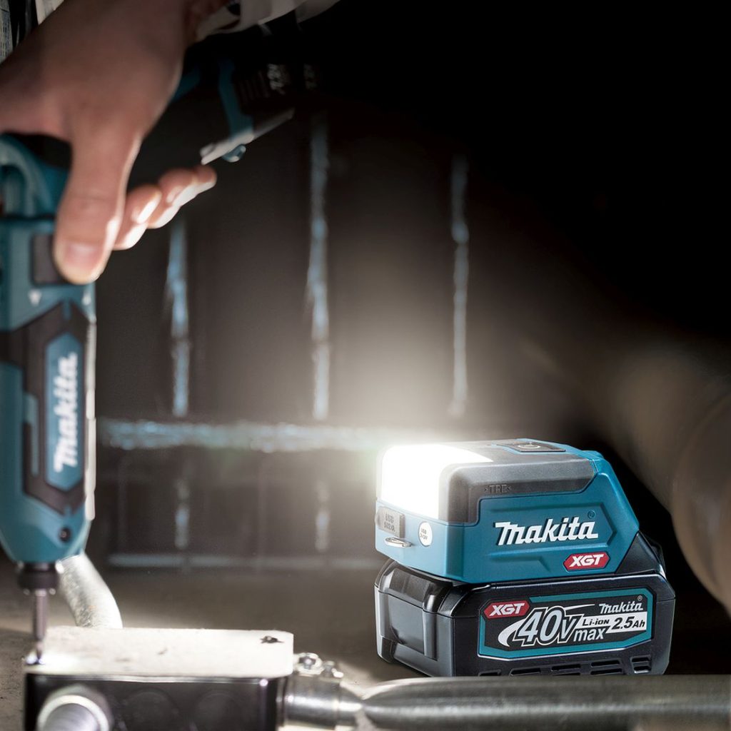 MAKITA LED-valaisin XGT. Kuvassa henkilö pimeässä asentamassa sähkörasiaa LED-valaisin XGT:tä apuna käyttäen.