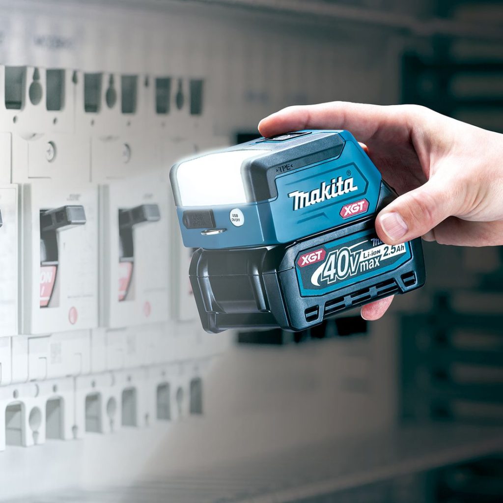 MAKITA LED-valaisin XGT. Kuvassa henkilö pimeässä valaisemassa sähkökaappia LED-valaisin XGT:n avulla.