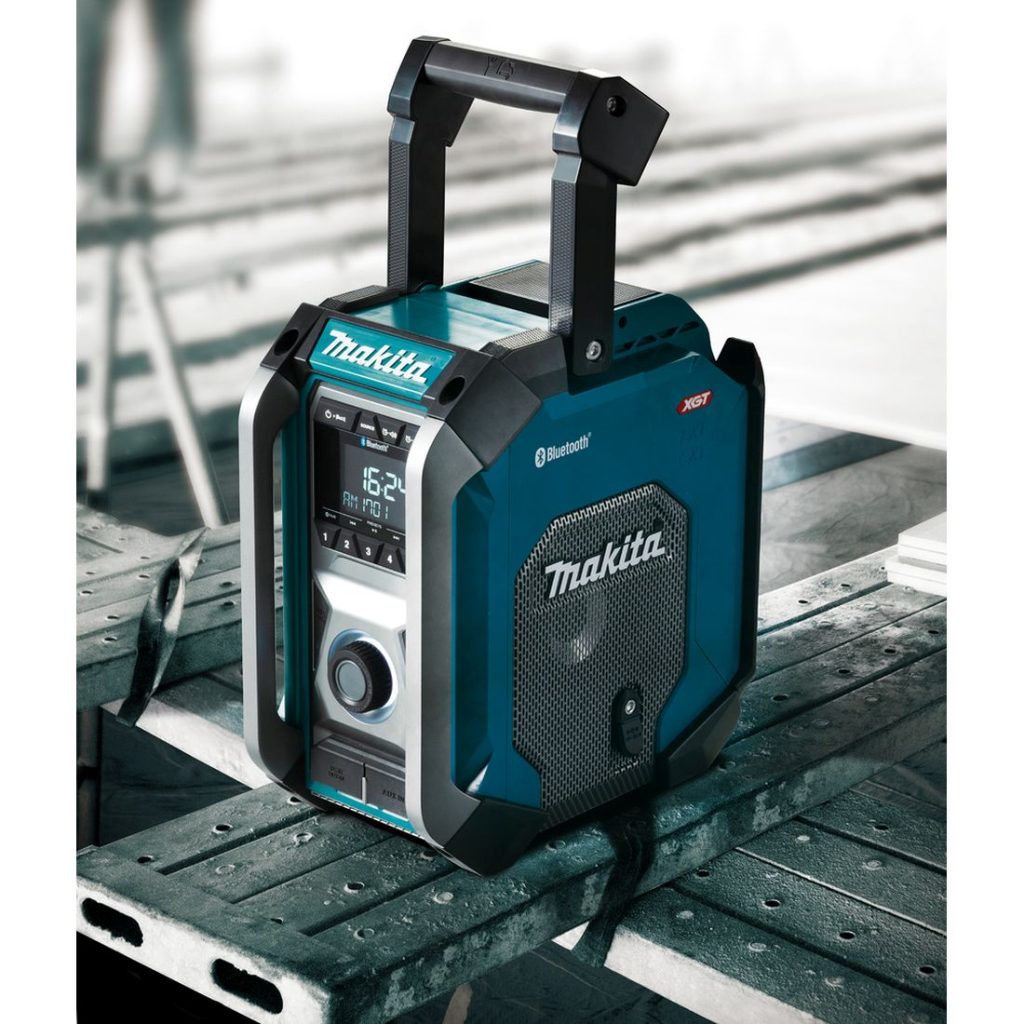 MAKITA Radio ja Bluetooth kaiutin CXT, LXT, XGT. Kuvassa Radio ja Bluetooth kaiutin CXT, LXT, XGT työmaalla kävelytason päällä. Kuva oikealta etuyläviistosta.