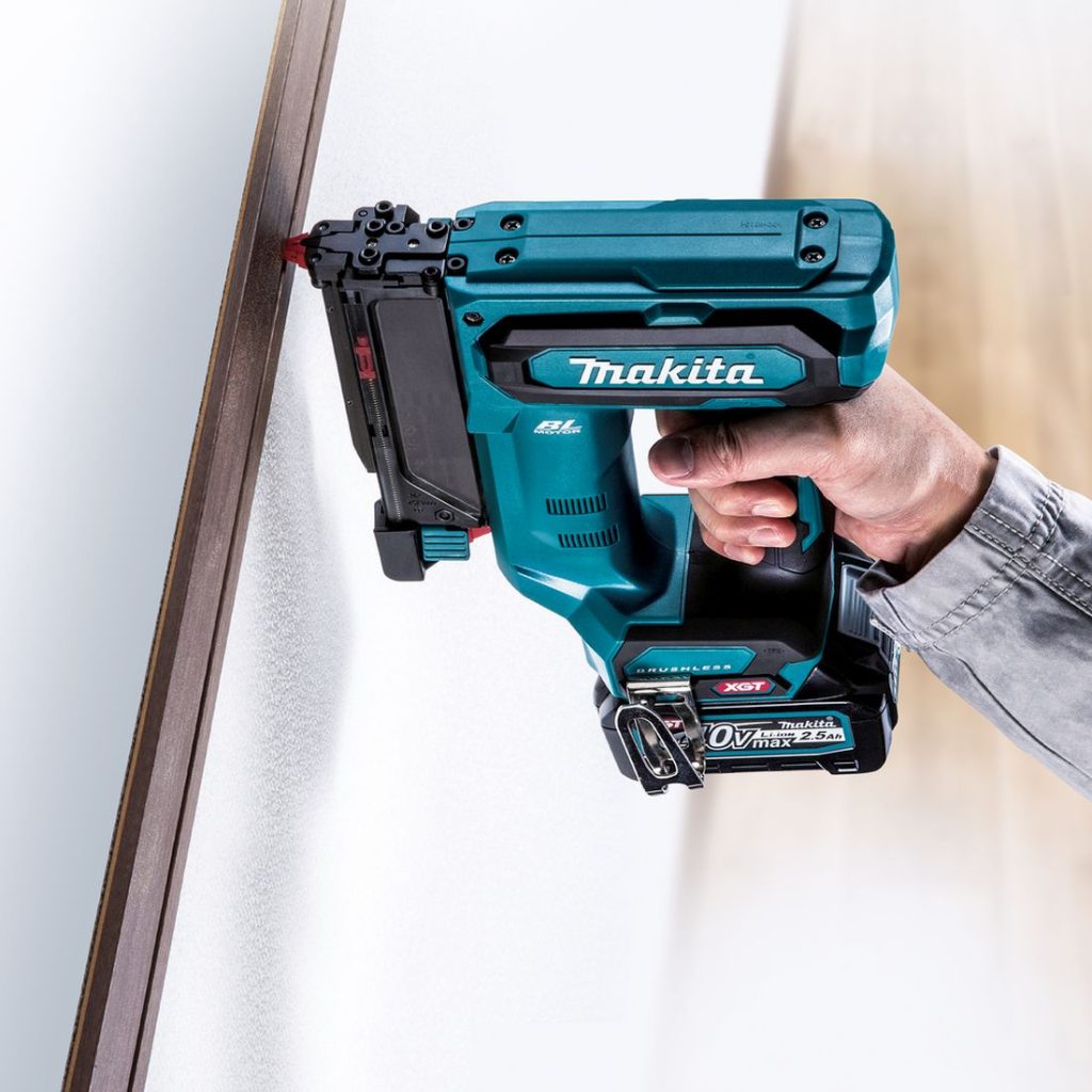 MAKITA Pinninaulain XGT. Kuvassa henkilö naulaamassa koristelistaa seinään Pinninaulain XGT:n avulla.