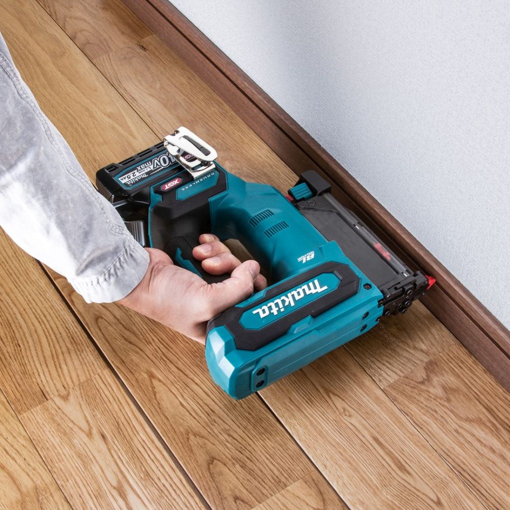 MAKITA Pinninaulain XGT. Kuvassa henkilö naulaamassa lattialistaa seinään Pinninaulain XGT:n avulla.