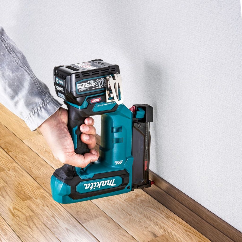 MAKITA Pinninaulain XGT. Kuvassa henkilö naulaamassa lattialistaa seinään Pinninaulain XGT:n avulla.