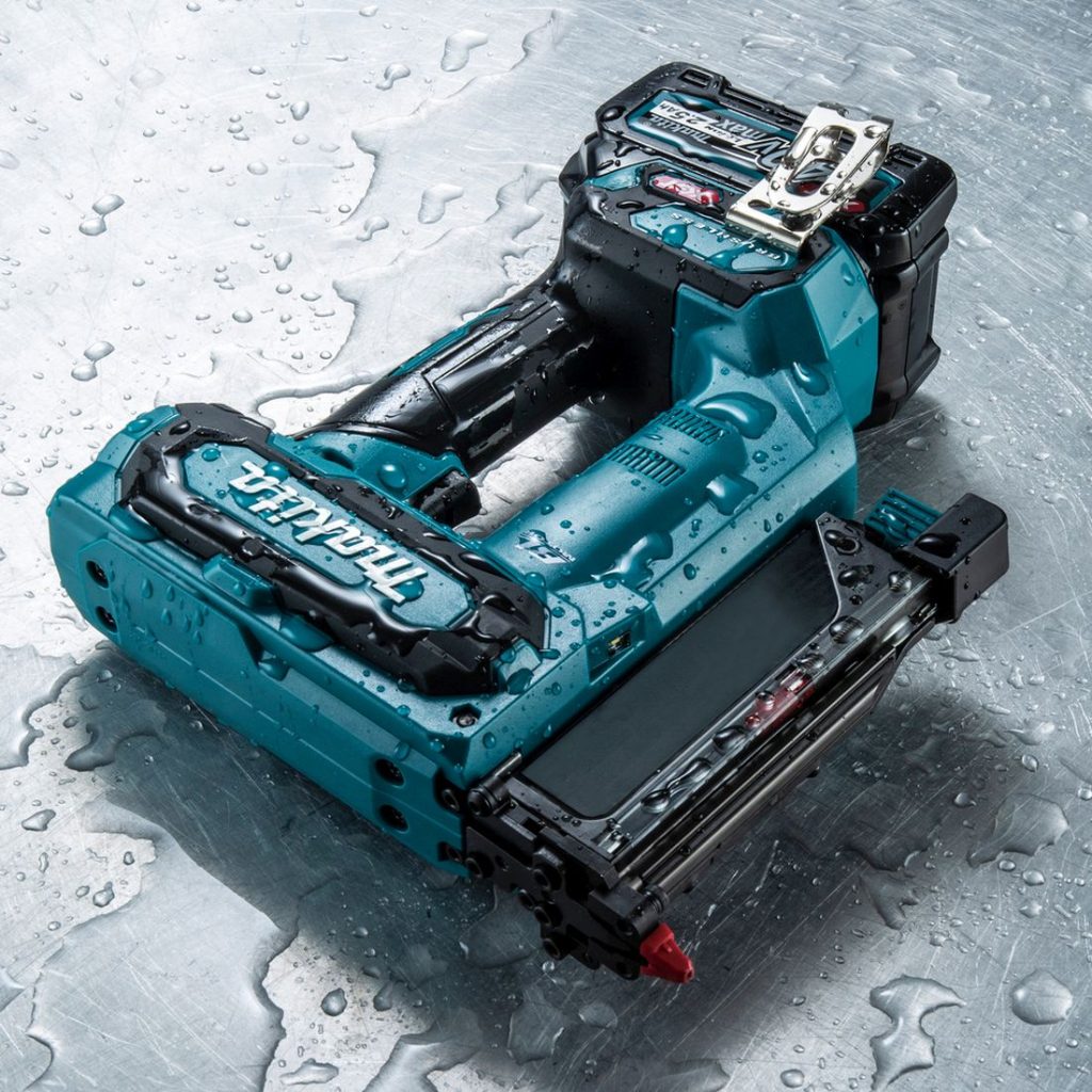 MAKITA Pinninaulain XGT. Kuvassa Pinninaulain XGT peltilevyn päällä. Naulain peltilevy vesiroiskeiden peittämänä.