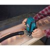 MAKITA Yläjyrsin. Kuvassa henkilö jyrsimässä puuhun Makitan logotekstiä yläjyrsimen avulla akryylisapluunaa hyväksikäyttäen.