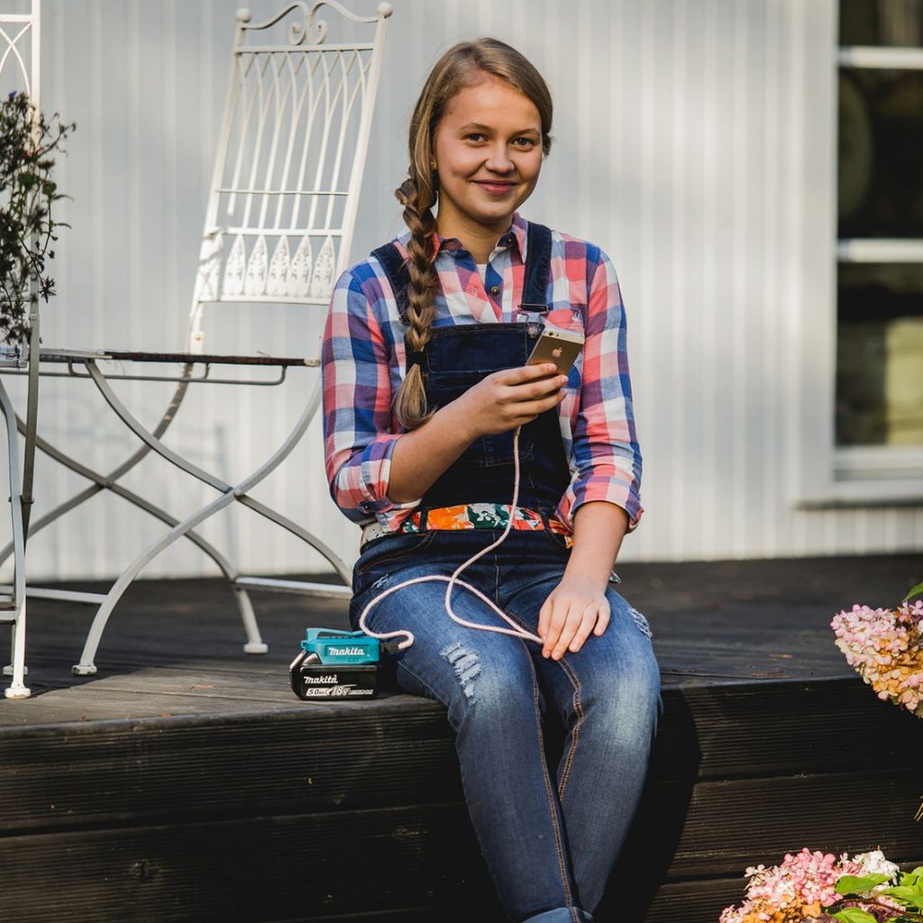 MAKITA Akkuadapteri LXT. Kuvassa henkilö katsomassa matkapuhelintaan Akkuadapteri LXT:n pidentäessä matkapuhelimen akun kestoa.