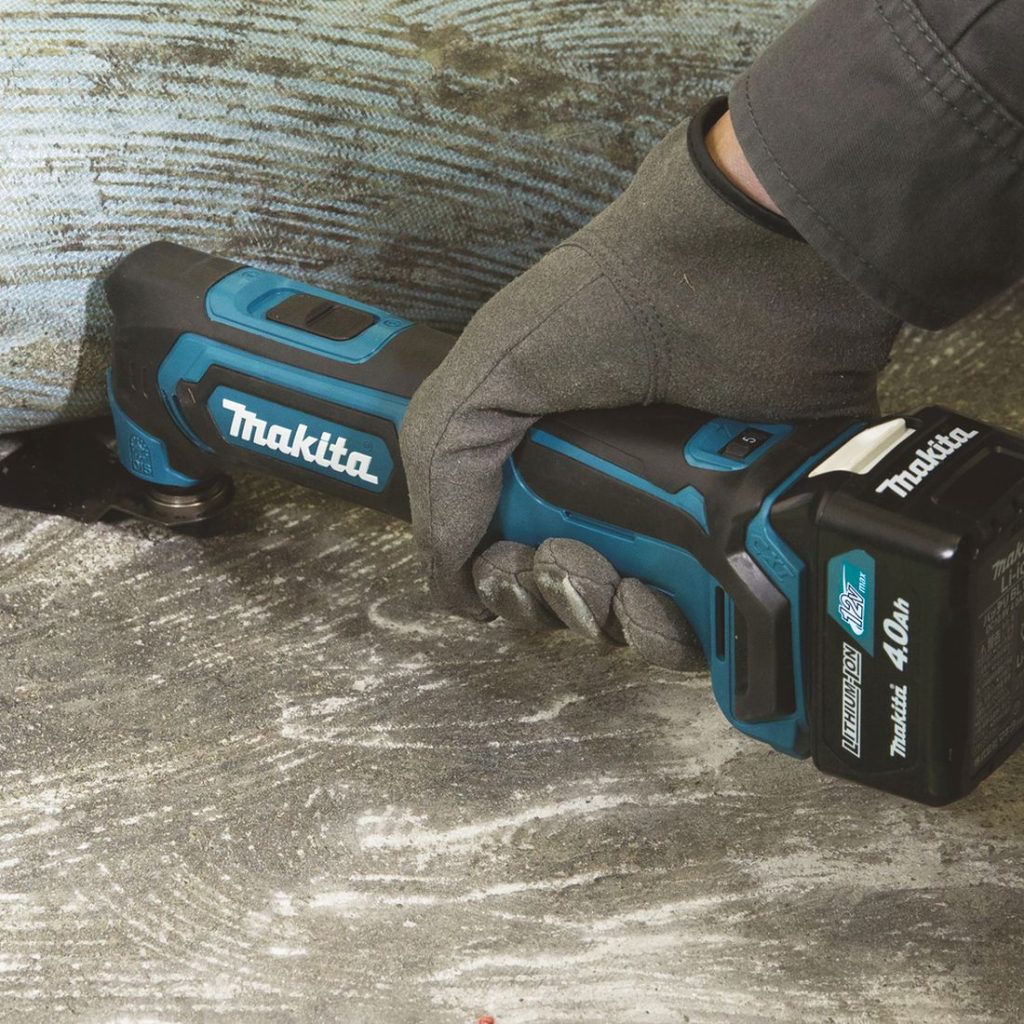 MAKITA Monitoimikone CXT. Kuvassa henkilö leikkaamassa rakoa betoniseinän ja lattian väliin Monitoimikone CXT:n avulla.