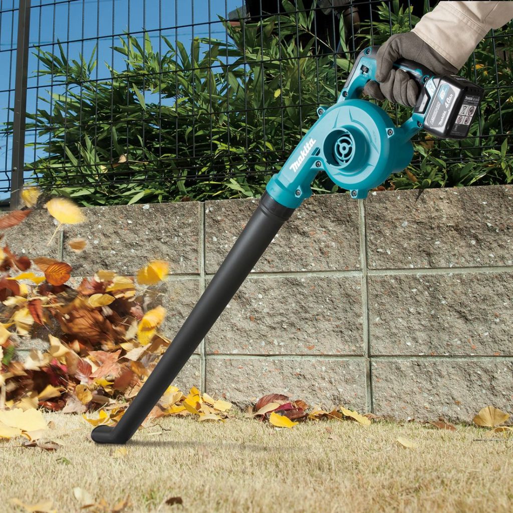 MAKITA Puhallin CXT. Kuvassa henkilö puhaltamassa lehtiä Puhallin CXT:n avulla.