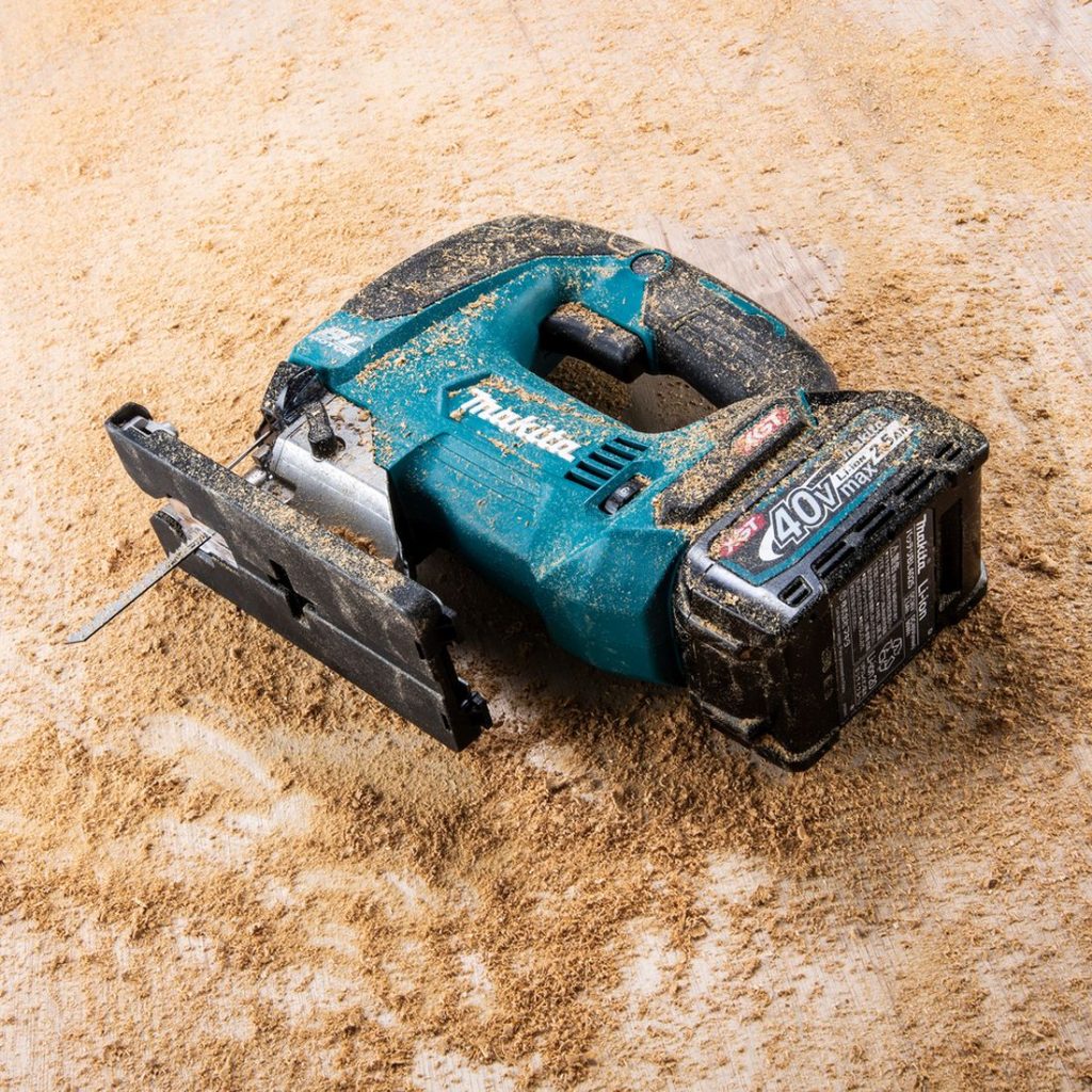 MAKITA Pistosaha XGT. Kuvassa Pistosaha XGT puisen lankun päällä kyljellään sahanpurun peittämänä.