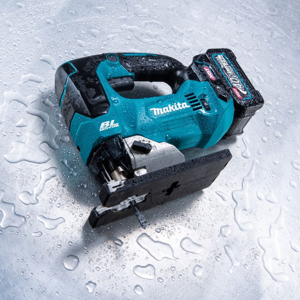 MAKITA Pistosaha XGT. Kuvassa Pistosaha XGT teräslevyn päällä kyljellään vesiroiskeiden peittämänä.